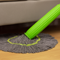 Green and gray mop cleaning a wooden floor with a beige sofa in the background