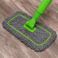 Gray microfiber mop with green handle on a wooden floor