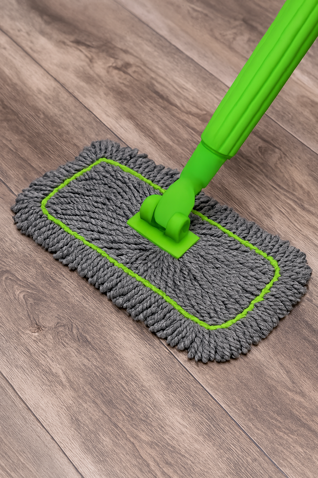 Gray microfiber mop with green handle on a wooden floor