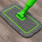 Gray microfiber mop with green handle on a wooden floor